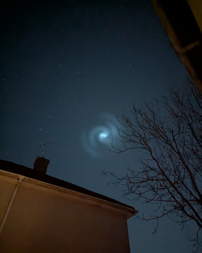 Mysterious spiral illuminates night sky above UK, creating a striking celestial display.