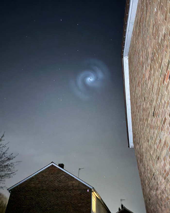 Mysterious spiral in night sky above UK houses, baffling viewers and stirring curiosity.
