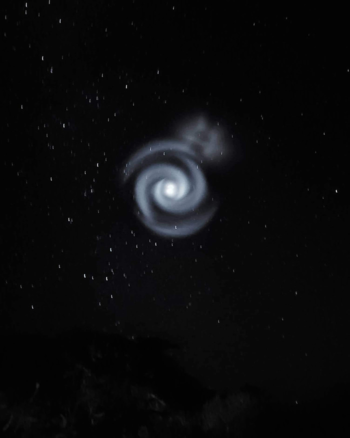 Mysterious spiral pattern appears in the night sky above the UK, surrounded by stars.