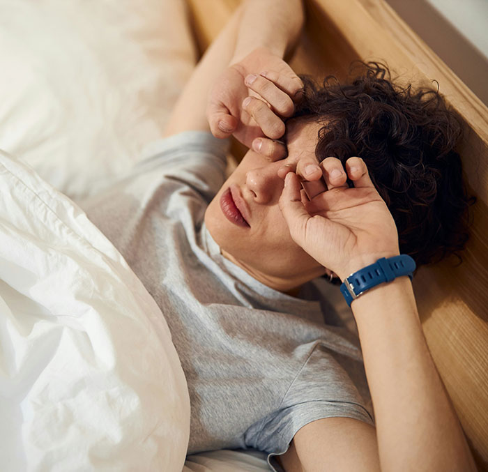Joven en cama frotándose los ojos después de despertar, representando decisiones espontáneas que cambiaron vidas.