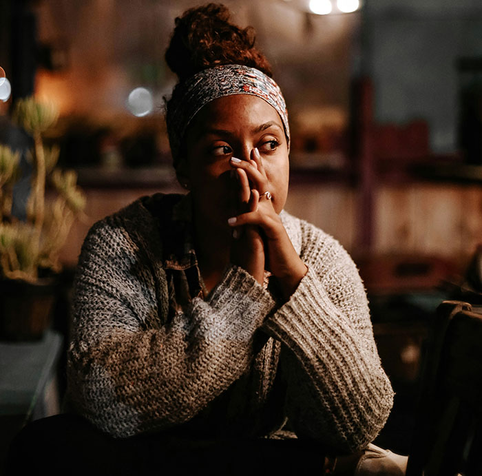 Woman in deep thought, wearing a headband and sweater, exemplifying life-saving decisions.