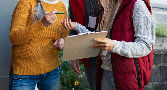 Personas conversando al aire libre, con clipboard y bolígrafo, ilustrando decisiones espontáneas que salvaron vidas.