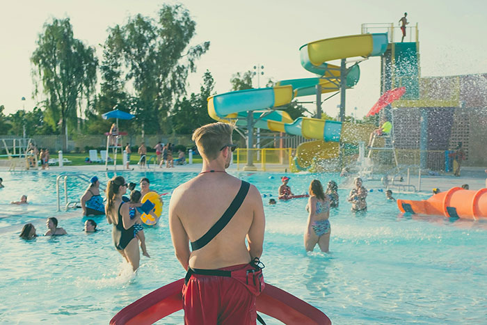 Salvavidas vigilando piscina con toboganes, simbolizando decisiones espontáneas que salvan vidas en momentos inesperados.