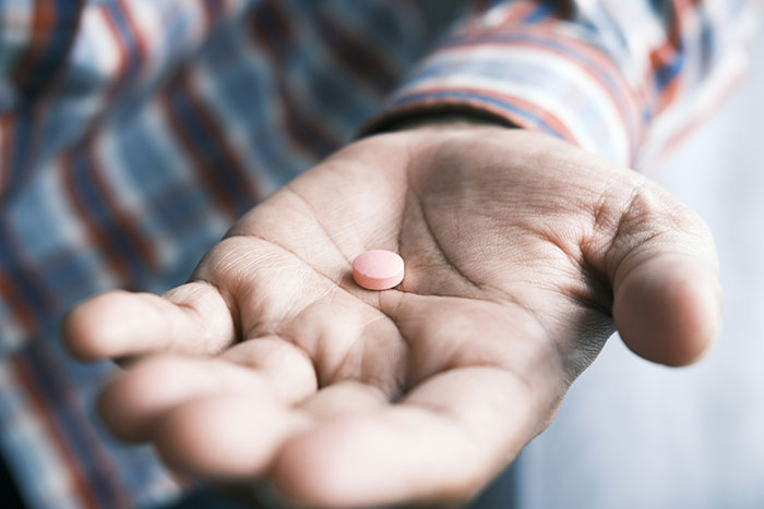 Hand holding a pink pill, symbolizing a life-saving split-second decision.