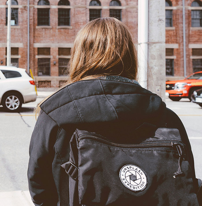 A person with a backpack stands by the street, facing brick buildings, symbolizing split-second decision moments.