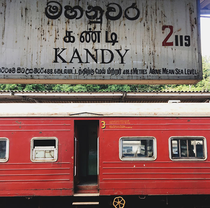 Red train at Kandy station with sign above, highlighting travel safety. Red train at Kandy station with sign above, highlighting travel safety.