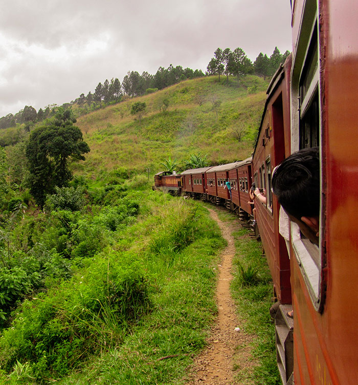 Tourist leans out of moving train in scenic landscape for photos, focusing on adventure and caution. Tourist leans out of moving train in scenic landscape for photos, focusing on adventure and caution.