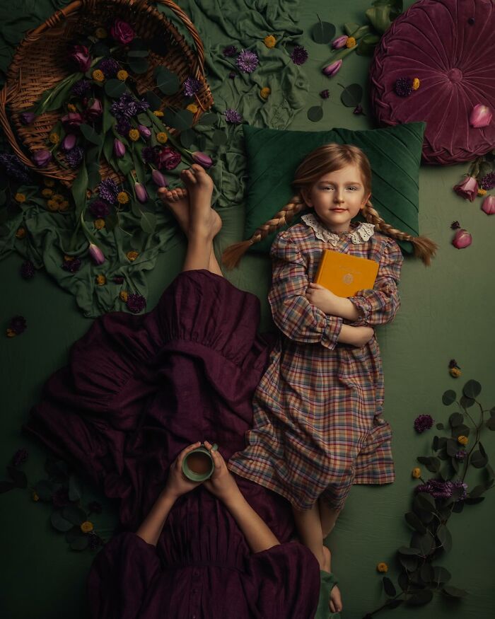 Mother with a cup and child holding a book, surrounded by flowers, capturing the magic of childhood in an artistic setting.