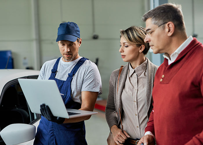 Mechanic shows two professionals a laptop in a workshop, illustrating malicious compliance at work. Mechanic shows two professionals a laptop in a workshop, illustrating malicious compliance at work.