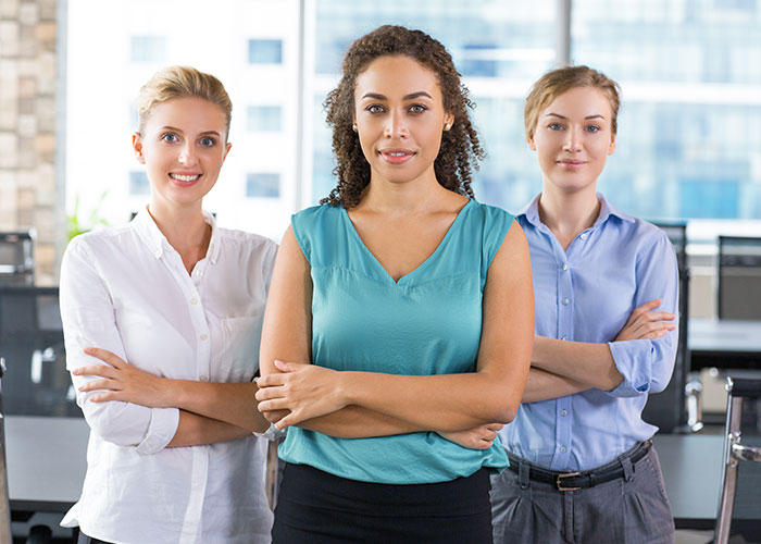 Three professional women standing confidently in an office setting. Three professional women standing confidently in an office setting.
