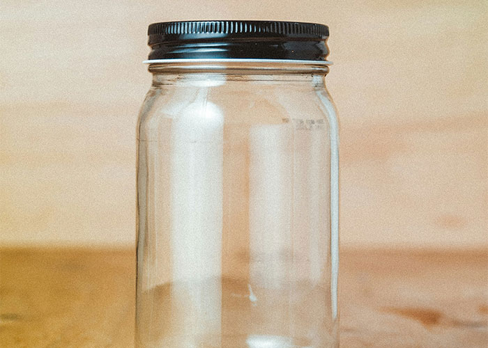 An empty glass jar with a black lid on a wooden surface, representing bizarre gym stories.