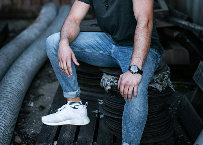 Man in casual outfit sitting outdoors on gym equipment.