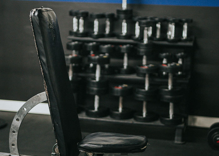 Empty gym bench with dumbbells in background, highlighting bizarre gym moments.