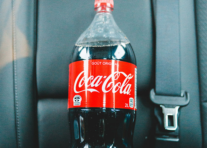A 2-liter Coca-Cola bottle on a car seat, possibly related to bizarre gym activities.