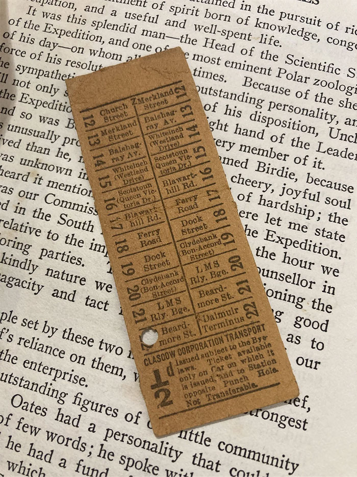 Vintage ticket bookmark on open book, showcasing a cool and unique find for book lovers.