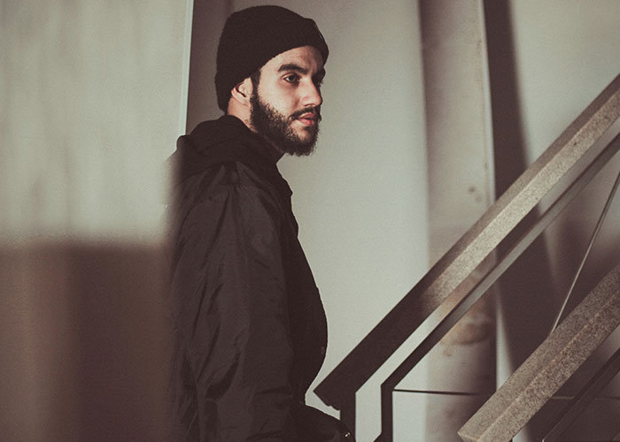Man in a dark jacket and beanie near stairs, symbolizing wild reasons to sue someone.