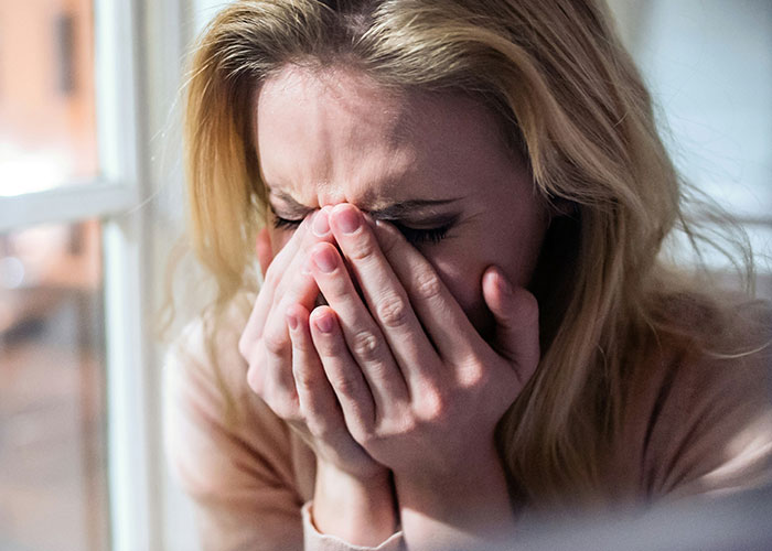 Woman in distress covering face, illustrating wild reasons for a lawsuit.
