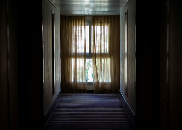 Dimly lit corridor with curtains over a window, representing reasons people decided to sue someone.