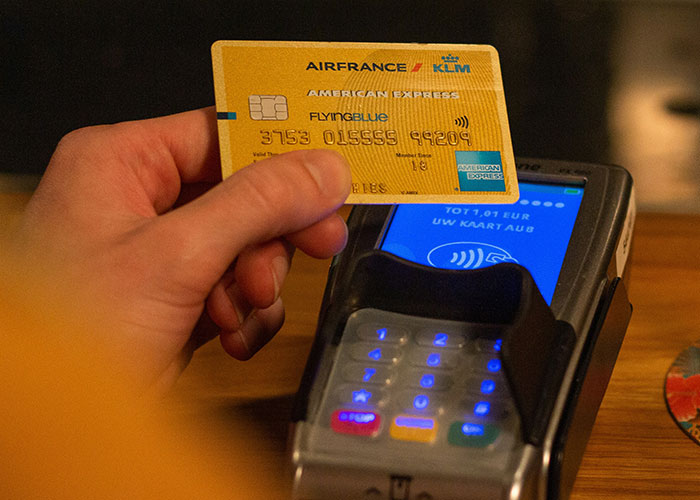 Hand holding a yellow credit card near a payment terminal, related to wild reasons people sue others.