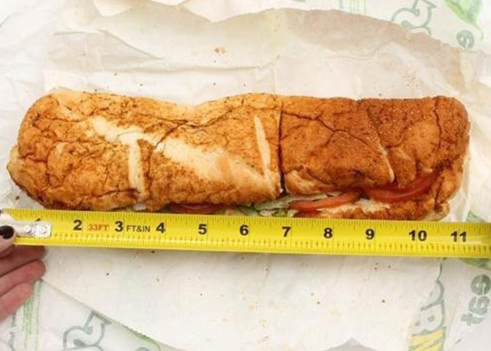Sandwich being measured with a tape measure for lawsuit reasons.