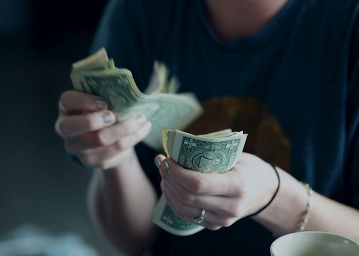 Person counting dollar bills, illustrating reasons people sue over money.