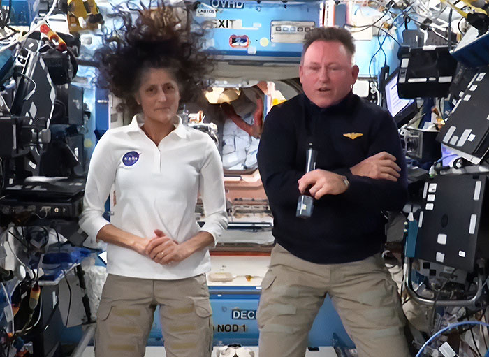 Astronauts in the space station, one with microphone, amidst SpaceX rescue delay causing public frustration. Astronauts in the space station, one with microphone, amidst SpaceX rescue delay causing public frustration.
