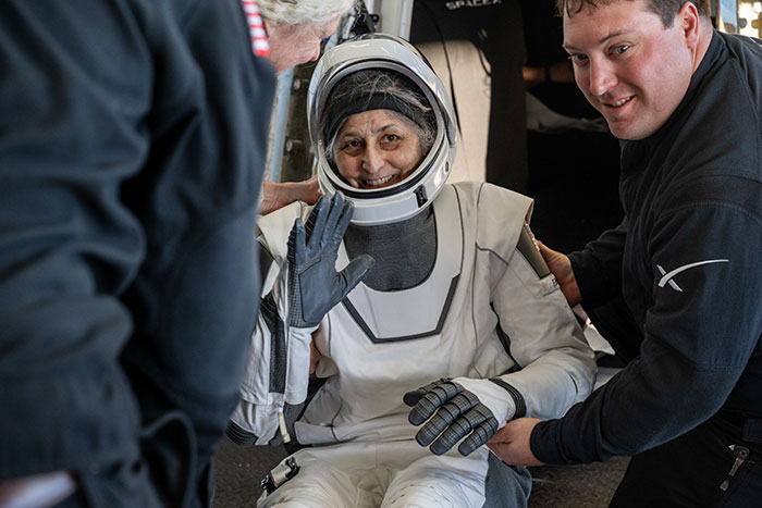 Astronaut in a space suit being assisted by doctors, highlighting concern as space professionals provide help.