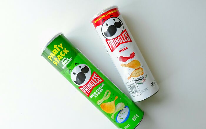 Two Pringles cans, one sour cream and onion, the other pizza flavored, on a white background.