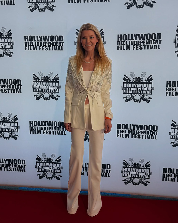Actress in elegant white suit on red carpet at movie premiere, showcases striking new look.
