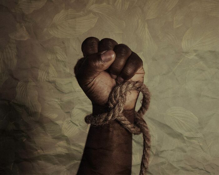 "Clenched fist bound with rope, symbolizing oppression, echoing dark side of history."