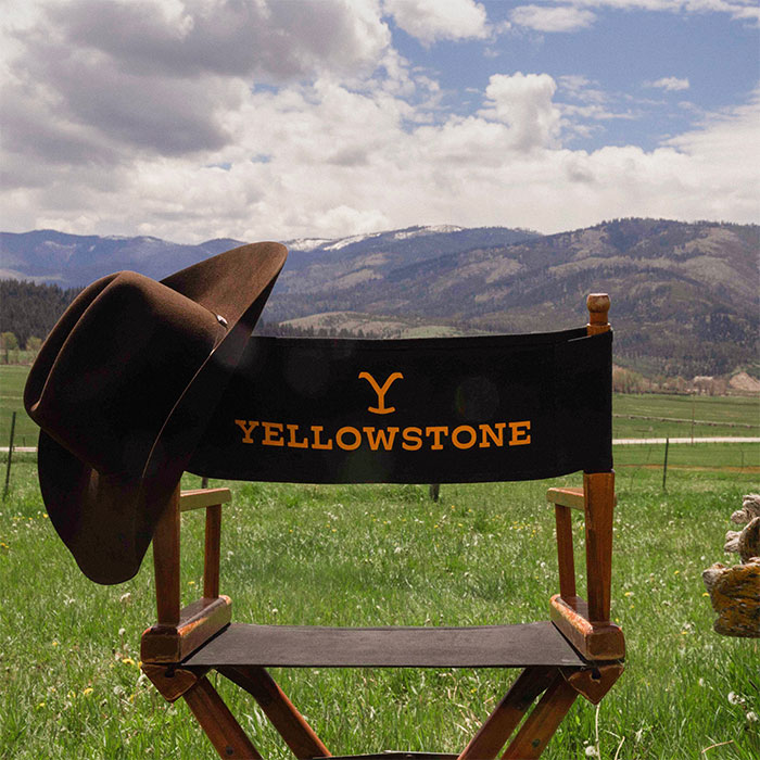 Director's chair labeled "Yellowstone" with a cowboy hat, set in a scenic mountain landscape.
