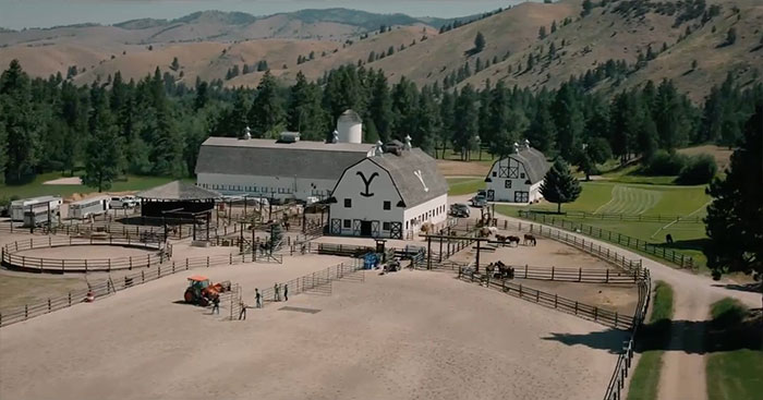 Ranch setting from Yellowstone series, showcasing expansive barns and mountainous background.