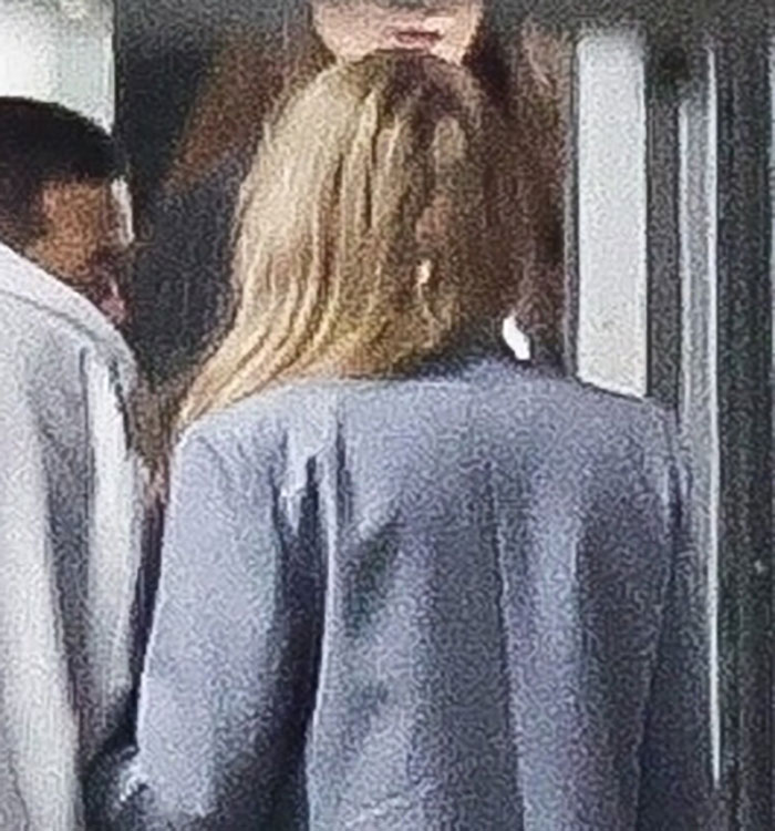 Back view of a woman with long hair in a stylish outfit, walking with a man in a white jacket, Taylor Swift date night ambiance.