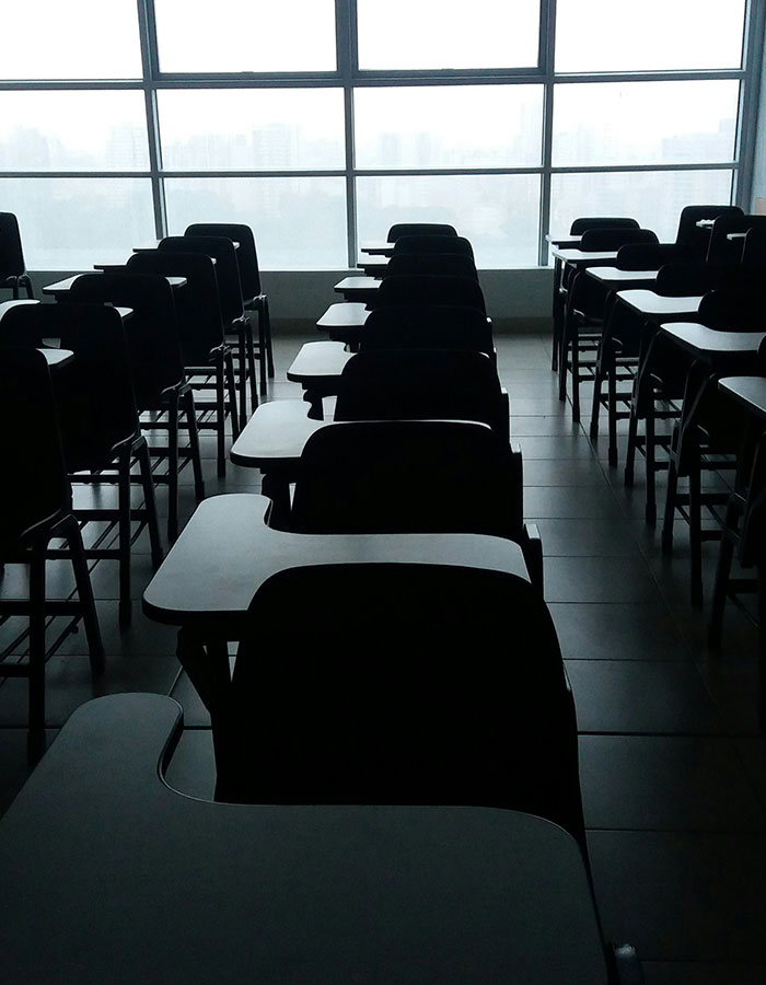 Empty classroom with rows of student desks in dim lighting, symbolizing the absence of a beloved teacher. Empty classroom with rows of student desks in dim lighting, symbolizing the absence of a beloved teacher.