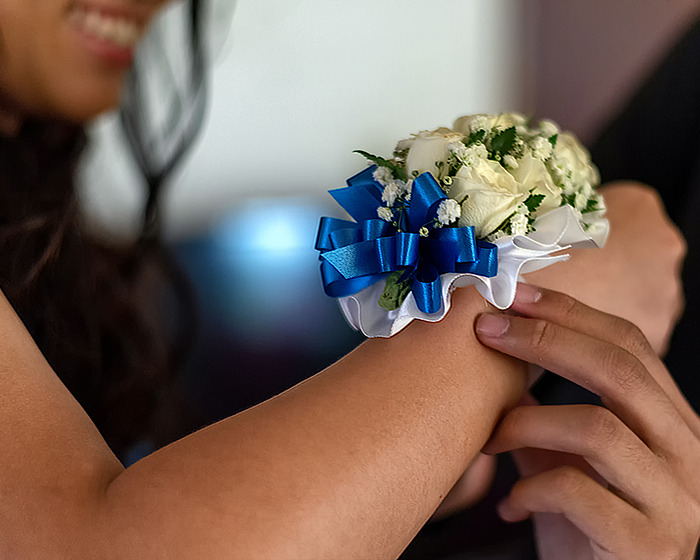 Person wearing a corsage with blue ribbon, highlighting prom night theme.