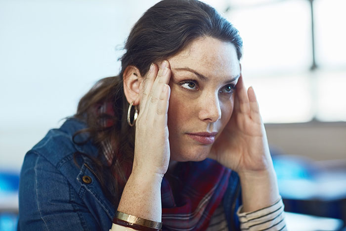 Woman looking frustrated, resting her head on her hands. Woman looking frustrated, resting her head on her hands.