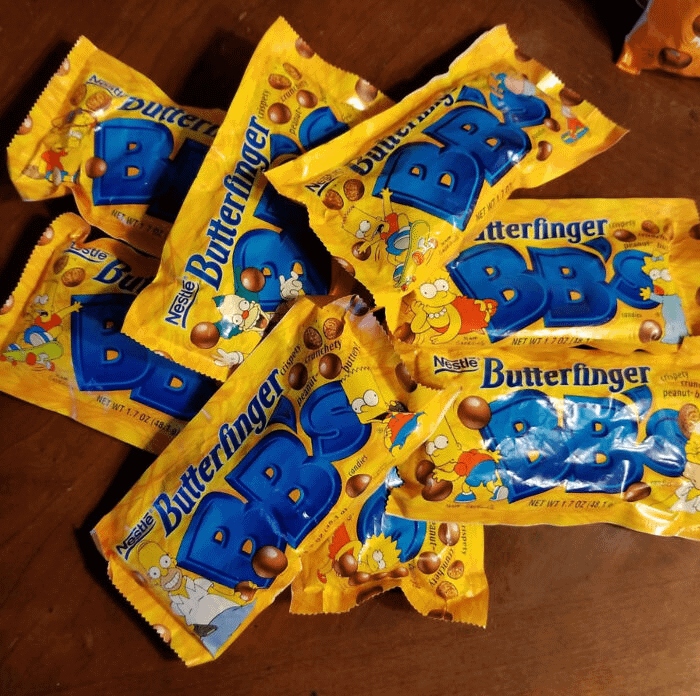 Packs of nostalgic Butterfinger BB's candy on a wooden surface.