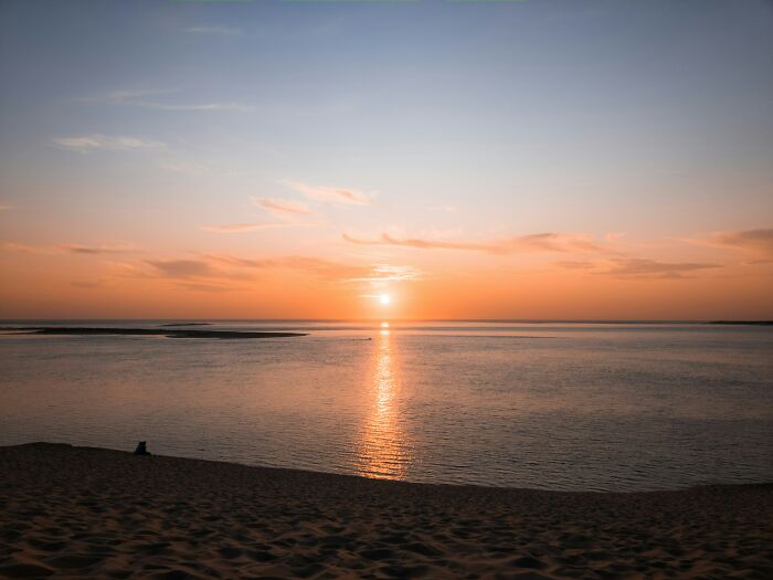 Stunning beach sunset with golden hues reflecting on the calm ocean waters.