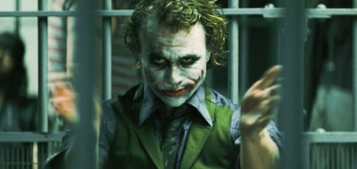 Character in clown makeup behind bars, infamous moment hyped up and matched expectations in film history.