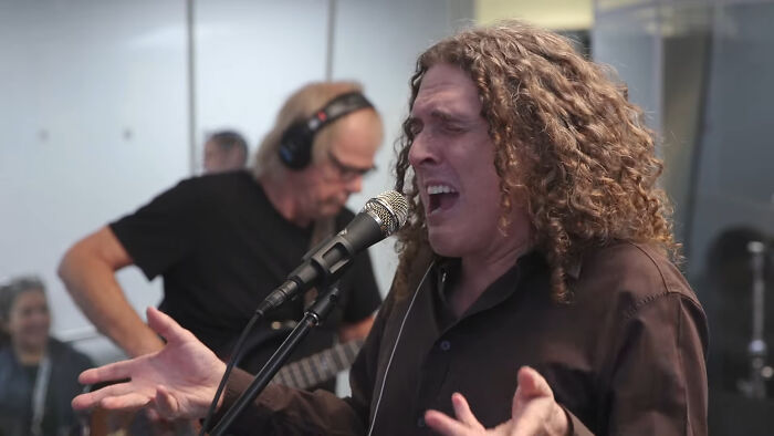 Musician passionately singing into a microphone during a live performance, capturing the hype and expectations.