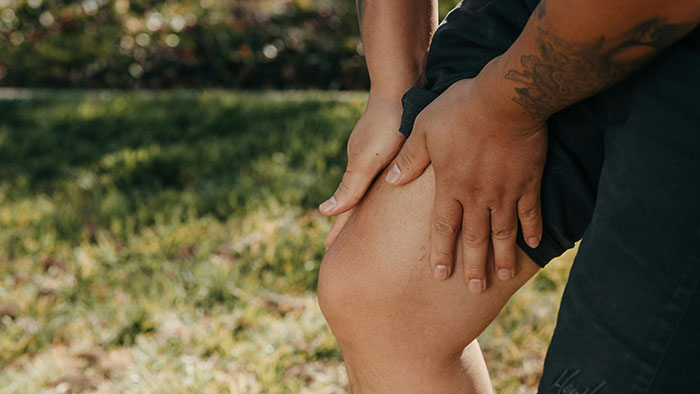 Person holding a knee outdoors, highlighting undiscovered aspects of the human body.