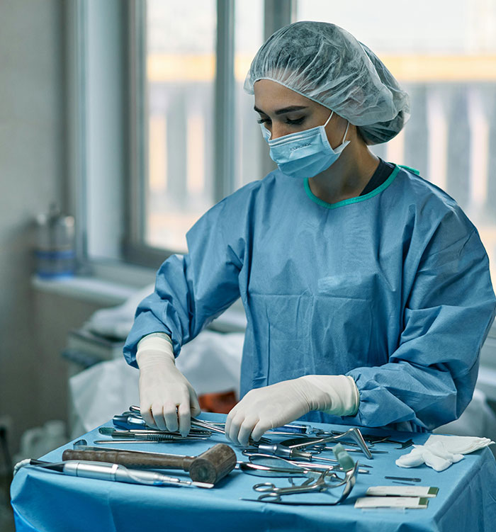 Health professional organizing surgical tools in an operating room, highlighting unknowns about the human body.
