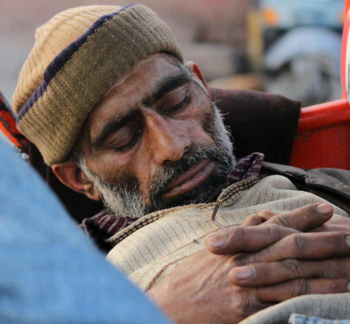 Sleeping man with folded hands, wearing a beanie and sweater, illustrating unknown aspects of the human body.
