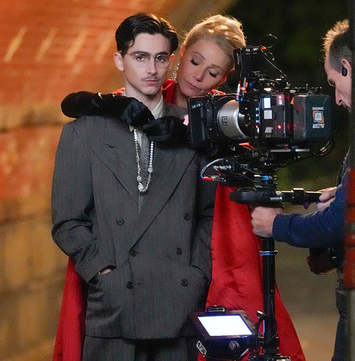 Film scene with actors in costume, close to a camera, filming a steamy scene, with the intimacy coordinator stepping back.
