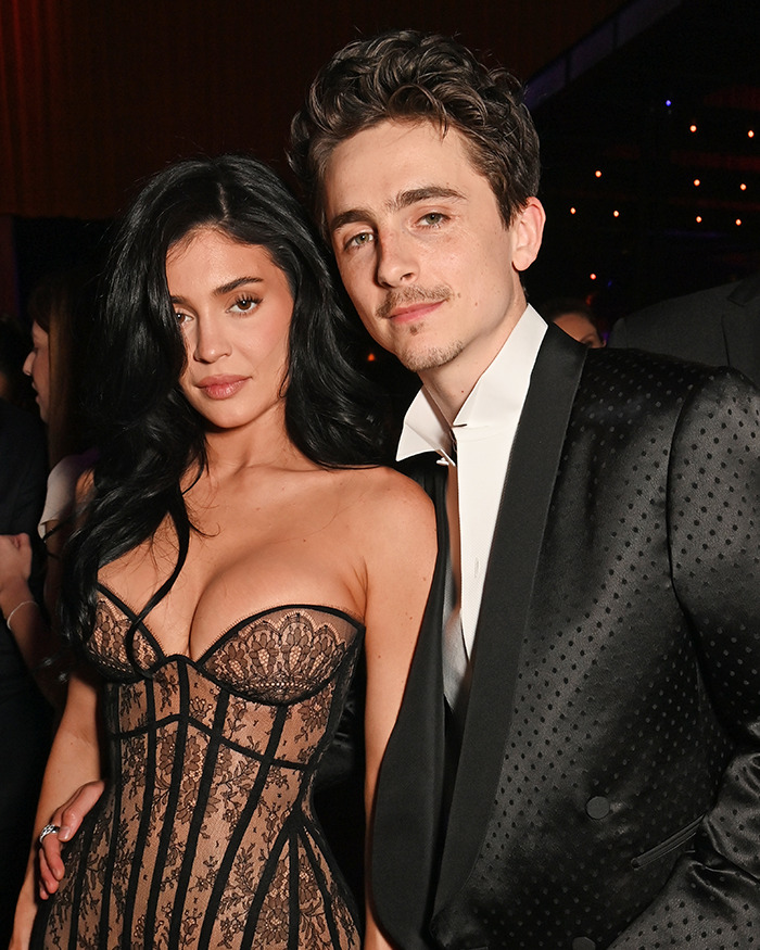 A man in a black tuxedo and a woman in a lace dress at a formal event.