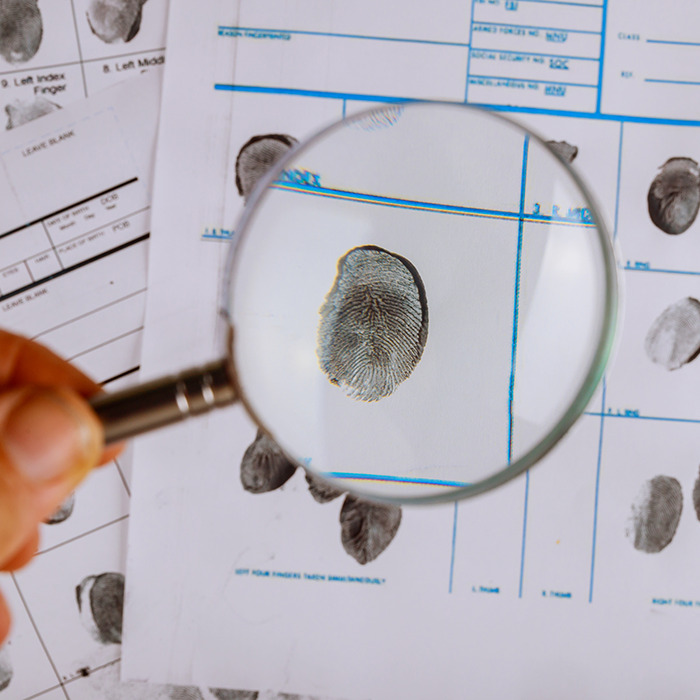 Fingerprint under a magnifying glass on investigation documents. Fingerprint under a magnifying glass on investigation documents.
