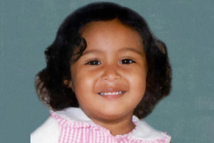 Andrea Michelle Reyes as a toddler with curly hair and a pink checkered dress. Andrea Michelle Reyes as a toddler with curly hair and a pink checkered dress.