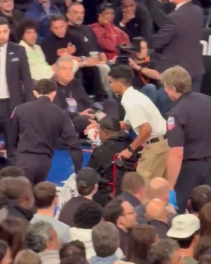 Steven Spielberg's daughter reacts in a crowded event scene, with people attending to someone sitting nearby.