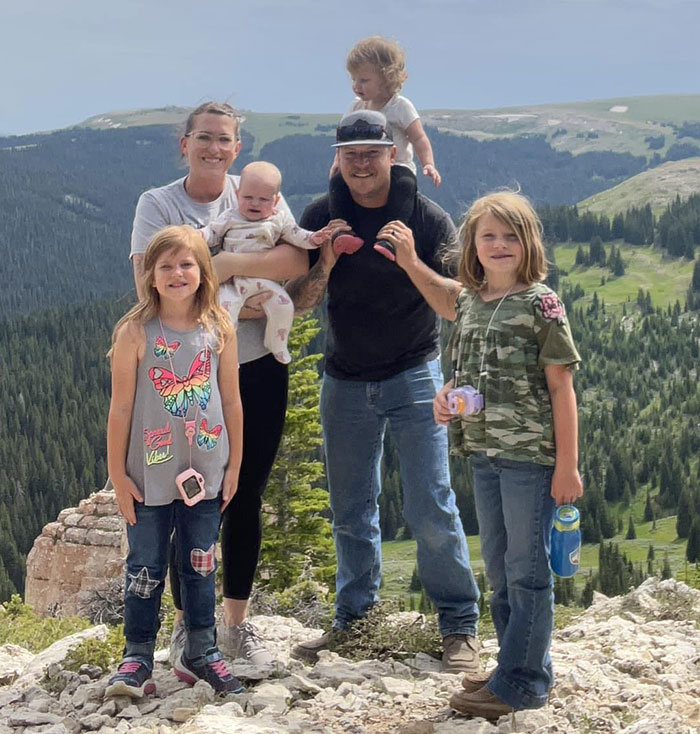 A family with children outdoors on a scenic mountain, greenery visible in the background. A family with children outdoors on a scenic mountain, greenery visible in the background.