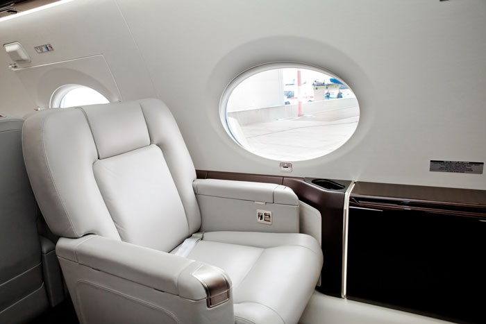 Airplane seat, spacious interior with window view, related to extra space needs for new hire.